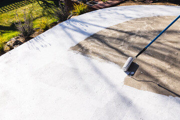 painting backyard or driveway concrete paving with paint roller, DIY and home improvement