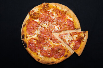 Pizza with tomato sauce, mozzarella and spicy salami on black fudal.