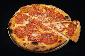 Pizza with tomato sauce, mozzarella and spicy salami on black fudal.