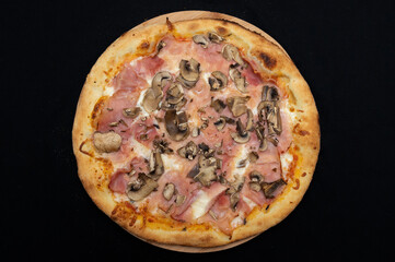Pizza with tomato sauce, mozzarella, smoked pork ham and mushrooms on a black background.