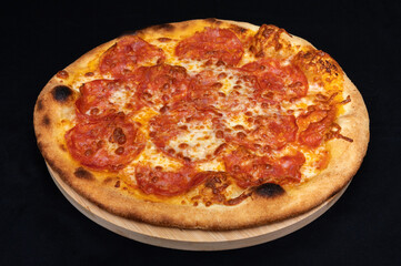 Pizza with tomato sauce, mozzarella and spicy salami on black fudal.