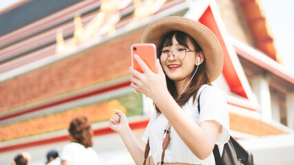 Young adult tourist asian woman using smart phone for listen music application. - obrazy, fototapety, plakaty