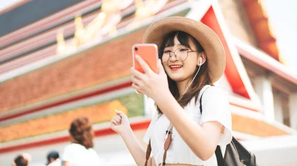 Foto op Plexiglas Young adult tourist asian woman using smart phone for listen music application. © dodotone