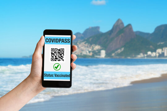 Hand holding mobile phone at beach with covidpass on display - Powered by Adobe