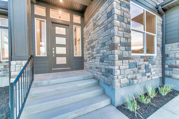 Home facade with stone brick wall and gray front door with frosted glass panels
