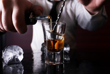 Barman preparing cocktail shots at the bar counter. Barman mixing drinks at the night club...