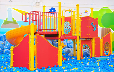 Fototapeta na wymiar red player where children can climb and slide down on blue rubber balls in the indoor amusement park