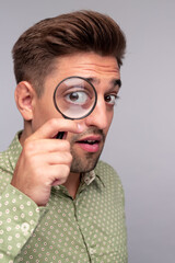 Curious man with magnifier looking at camera