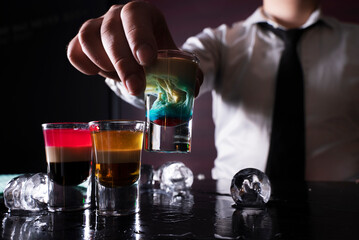 Barman preparing cocktail shots at the bar counter. Barman mixing drinks at the night club...