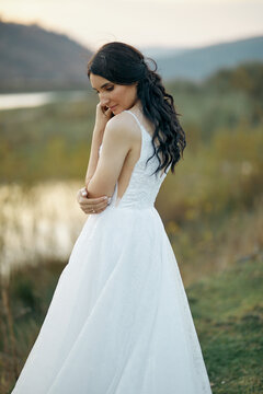 A beautiful brunette bride staying at the valley near the river. Outdoors