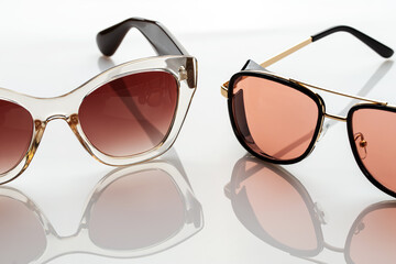 Sunglasses on a white reflective surface. Fashionable, stylish accessories. Use it for a vacation...