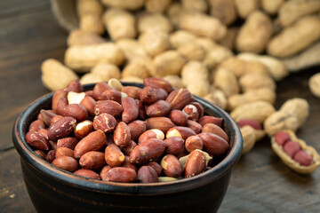 Peanuts in a clay plate on a wooden table. Inshell nuts.