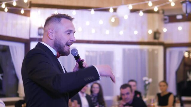 Minsk\Belarus - 01.07.21: Young Showman presenter with microphone at wedding. Male public speaker speaking at the microphone at event celebration