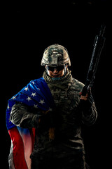 Naklejka premium Photo of soldier holding the USA flag in background. Special force United States soldier or military contractors holding rifle. Image on background. soldier, army, war, weapon and technology concept.