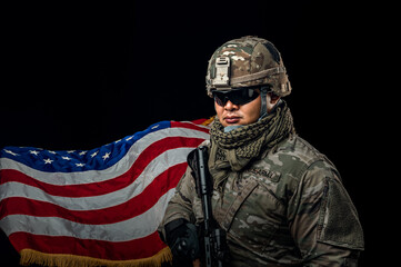 Photo of soldier holding the USA flag in background. Special force United States soldier or military contractors holding rifle. Image on background. soldier, army, war, weapon and technology concept.