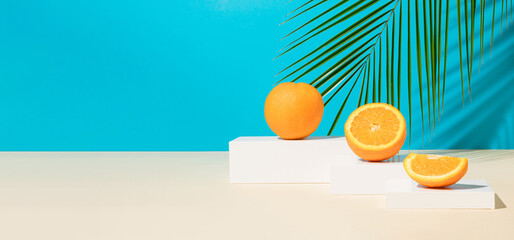 Modern still life with fresh and ripe orange fruit on podium or pedestal on a blue background with...