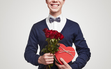 Cheerful young man with roses and gift box