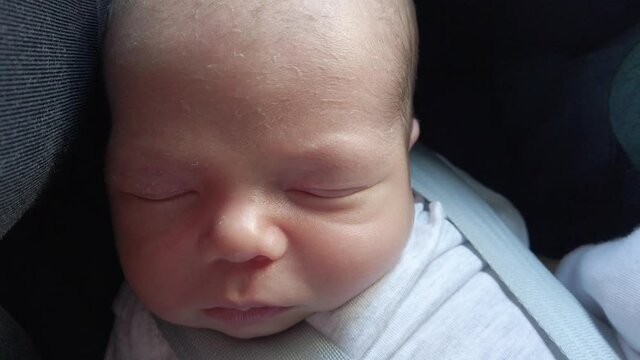 Close up of newborn baby boy, sleeping in a child car seat
