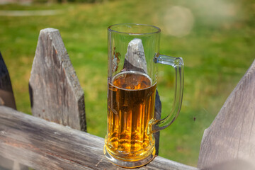Glass of beer leaning against a wooden fence with wooden background