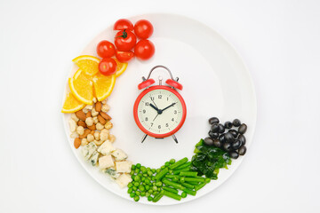 Diet and lunchtime, Intermittent fasting concept. Vegetables, oranges, cheese, nuts and clock on a...