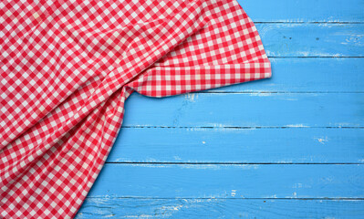 folded red and white cotton kitchen napkin on a wooden blue background
