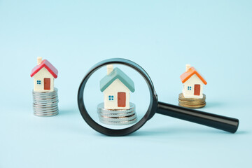 Miniature houses and stacks of coins under a magnifying glass. The concept of real estate,...
