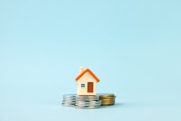 Miniature house standing on stacks of coins. The concept of real estate, mortgage, home insurance,...