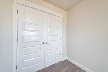 Linen or wardrobe closet with closed white double doors inside a house
