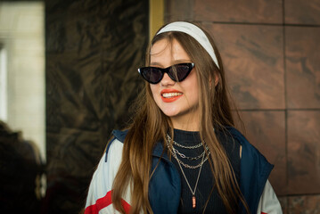 Beautiful country girl in 90s style. Back in time 90s 80s. Stylish girl in retro colourful vintage coat. dressed in street style clothes with chains around neck for a walk. Youth and lifestyle concept