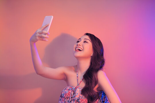 Young woman taking selfie photo on smartphone looking camera laughing happy.