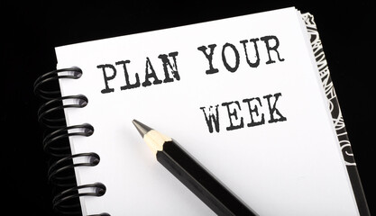 Plan Your Week written text in small notebook on a black background