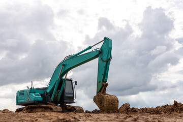 A muddy green backhoe parked on the ground.