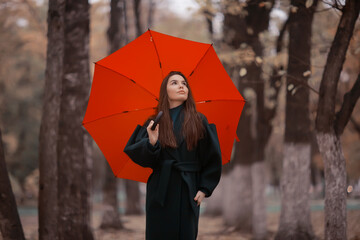 girl with umbrella posing in autumn park, october landscape lonely woman holding a red umbrella