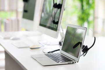 Headsets for call center teams are placed at a desk with a computer and laptop. while the team is in the break