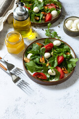 Healthy diet salad with arugula, mozzarella, mussels and vinaigrette dressing on a gray stone tabletop. Copy space.