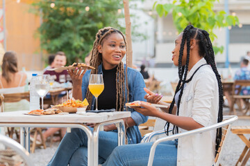 Afro american women enjoying food and drinks at an outdoors terrace