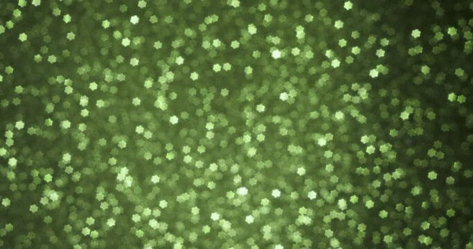 Rotating green bokeh in the shape of a star. Unusual bokeh, lens. Abstract festive background