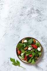 Healthy diet salad with arugula, mozzarella, mussels and vinaigrette dressing on a gray stone tabletop. Top view flat lay background. Copy space.