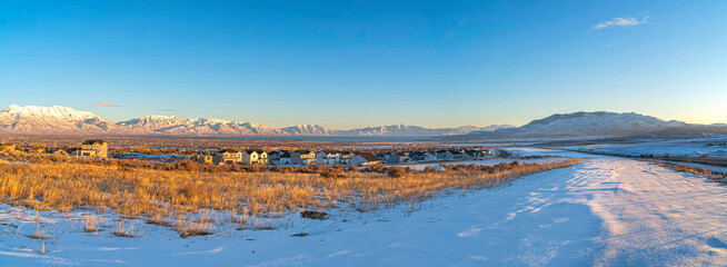 Naklejka premium Vast field of snow with large houses at Saratoga Springs, Utah with view of Wasatch Mountains