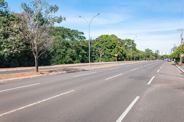 Fototapeta na wymiar Large avenue with a separated bike lane and green trees around. Nelly Martins avenue at Campo Grande MS, Brazil.
