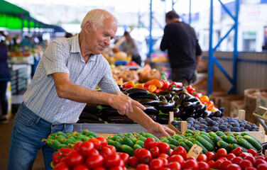 retired european man buying tomatoes in market