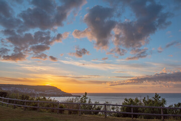 Sunset behind cliffs over sea in West Wales