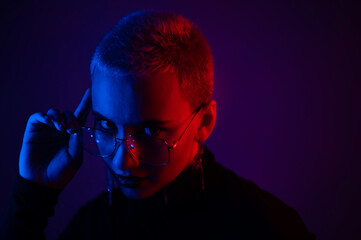 Portrait of beautiful young woman with short hair wearing glasses in neon light
