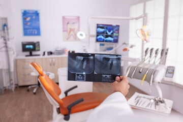 Radiologist man doctor analyzing medical teeth healthcare radiography after orthodontic surgery working in stomatology hospital office room. Orthodontist planning oral dental treatment