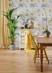 Decorative flower wallpaper background, wooden chair and cabinet style with green vase of plant, yellow carpet and home accessory style.