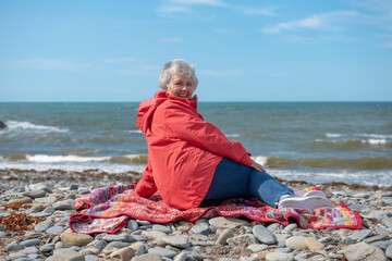 rear view image of senior woman sitting on beach, laughing at camera 