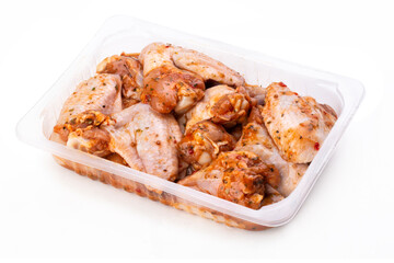 Raw spicy chicken wings for grilling in a transparent plastic box