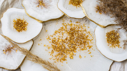 Cup holder, epoxy resin tray, stone cut, white marble with gold trim. White streaks of paint. Table setting decor, object aesthetics. Gloss, reflection. Stone effect. Blurred background. 