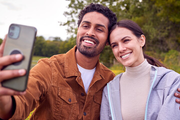 Couple On Walk In Countryside Taking Selfie On Mobile Phone