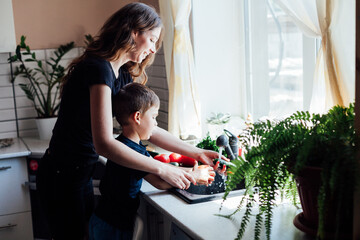 mother and son wash vegetables with water in the sink